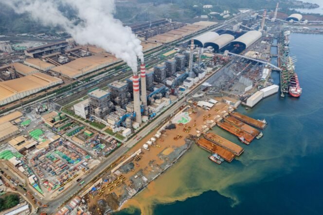 
 Indonesia Weda Bay Industrial Park (IWIP)’s huge enclosed facility is seen while chimneys emit smoke into the sky in Lelilef Sawai, Central Halmahera, North Maluku, Indonesia, on August 14, 2024. IWIP is currently the biggest player in Indonesia's nickel industry. The villagers are impacted by dust and smog from the mining activities, affecting their respiratory health. The coastal nickel mining facility stands on top of reclaimed land, previously a mangrove area, which limits access to local fishermen from neighboring Gemaf and Sagea, among other villages.
