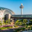 Changi Airport, Singapore - January 24, 2020: Changi Airport futuristic viewes with bridge between terminals at sunset time viewed through window